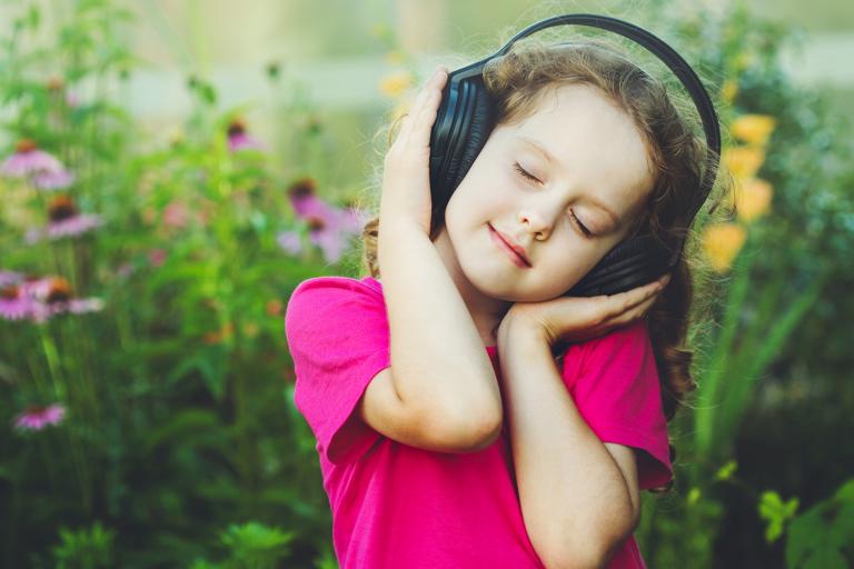 a little girl bopping to her headphones in a field of flowers